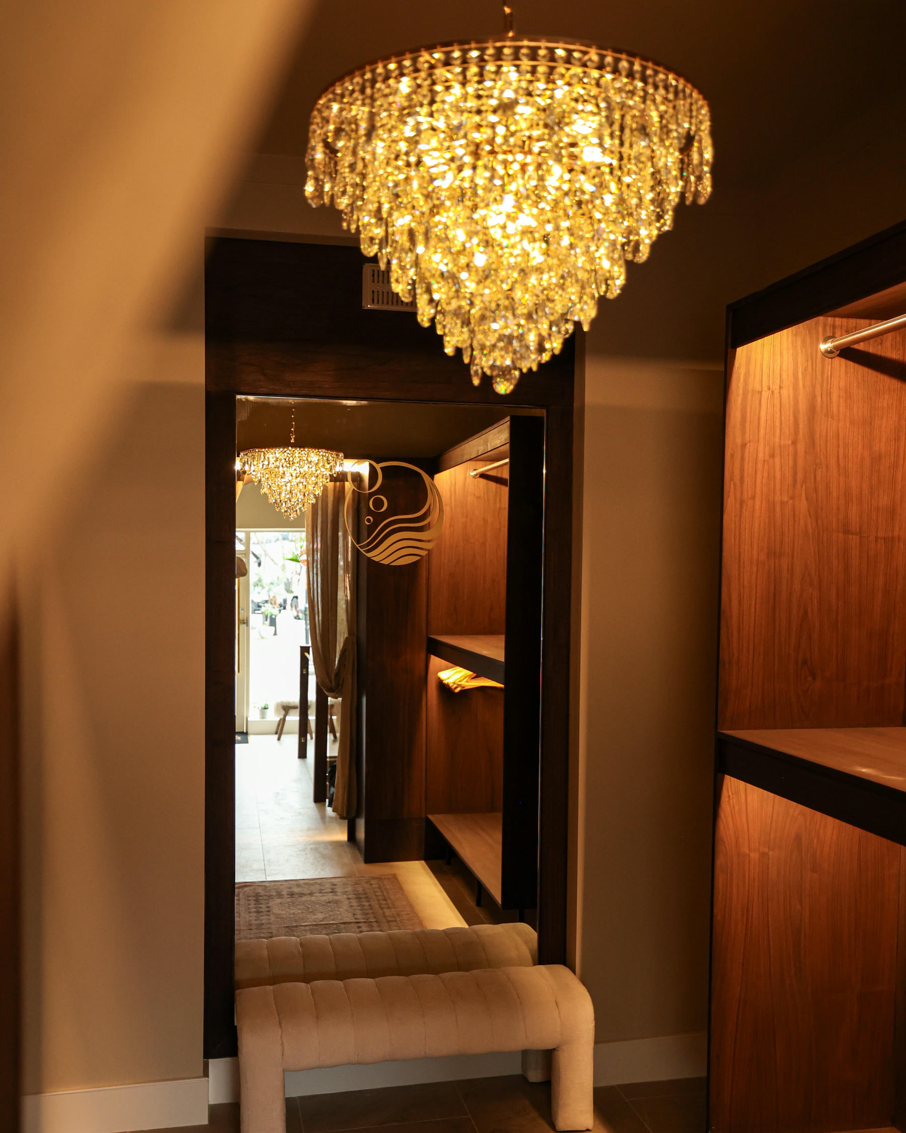 The London Laundry Club corridor: walnut walls, garments in covers and a crystal chandelier